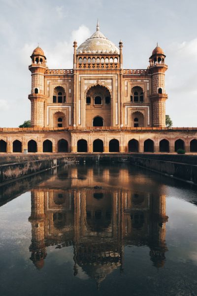 A large red and white domed building and it\'s reflection in water.