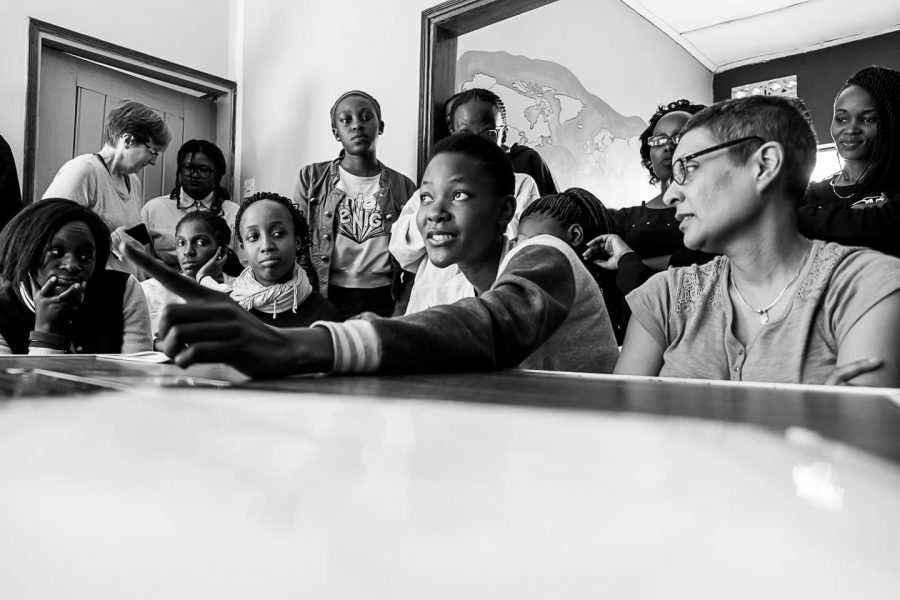 A class of Cameras for Girls with their photography teacher Amina Mohamed sitting at a table discussing the topic