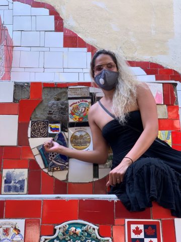 Milagros Rojas sitting in front of the tile with a Venezuelan flag at the Selaron Steps