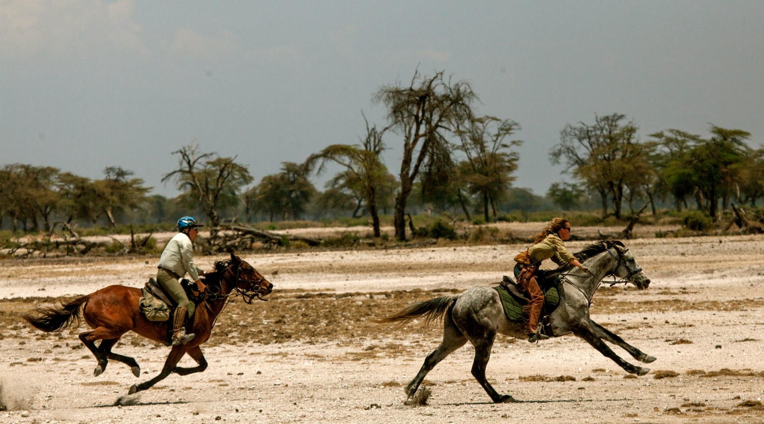 Two people on horseback at full speed during a safari with Kaskazi Horse Safaris out of Arusha Tanzania